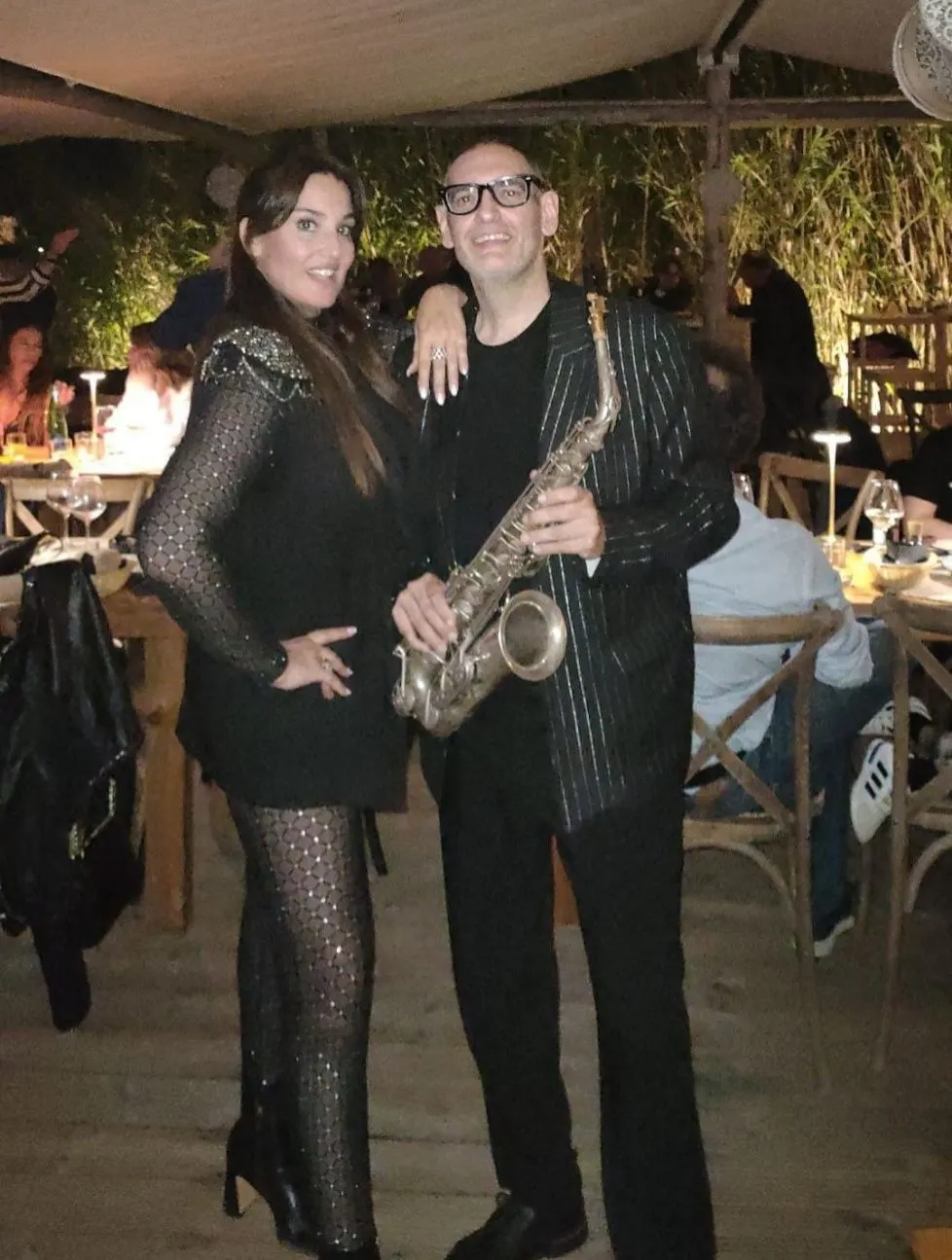 Chantal posa accanto al sassofonista durante un evento serale.