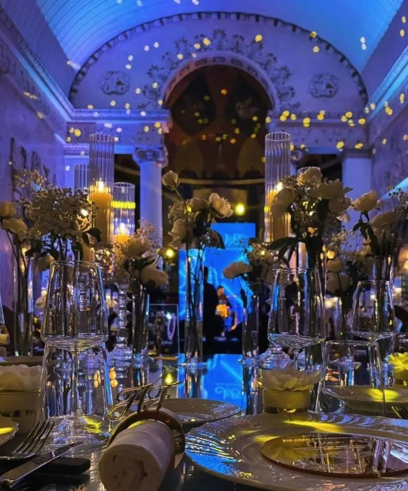 Sala ricevimenti elegante illuminata di blu, con la mise en place già pronta sui tavoli.